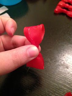 a hand holding a piece of red plastic in the shape of a flower on a table