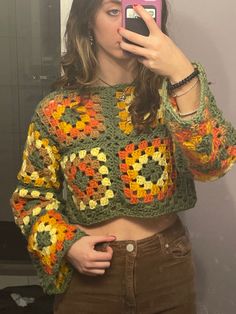 a woman taking a selfie in front of a mirror wearing a crochet sweater