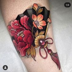 a woman's leg with flowers on it and a fan tattoo design in the center