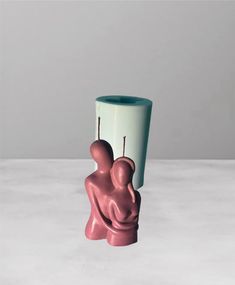 a pink and white vase with two people on it's sides, one holding the other