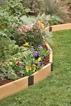 a garden filled with lots of different types of flowers and plants in wooden planters