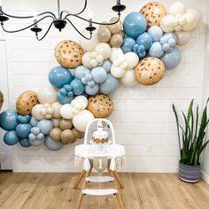 a baby's highchair in front of a wall with balloons on it