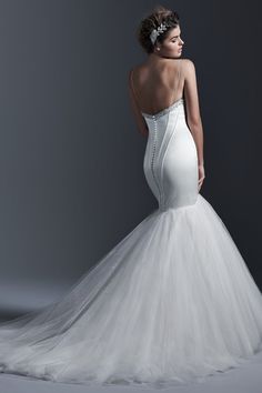 a woman in a white wedding dress is posing for the camera with her back to the camera