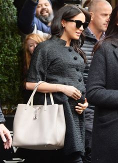 a woman carrying a white bag while walking down the street with other people behind her