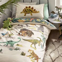 a child's bed with dinosaurs and plants on it