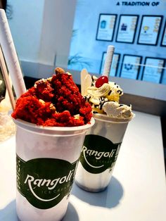 two cups filled with ice cream and toppings on top of a white table next to each other