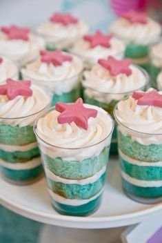 small cupcakes with white frosting and pink stars are on a cake plate