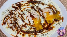 a white plate topped with eggs covered in sauce and seasoning on top of it