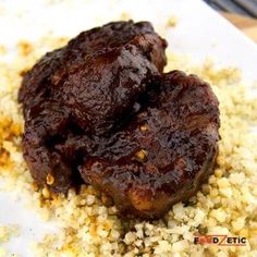 two pieces of meat sitting on top of some couscous