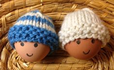 two eggs with knitted hats sitting in a basket