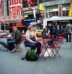 people sitting at tables in the middle of a city