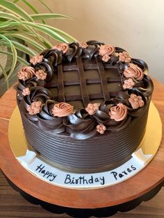 a birthday cake with chocolate frosting and flowers on the top is sitting on a table