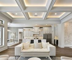 a living room filled with white furniture and lots of windows on top of wooden flooring