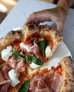 someone is taking a slice of pizza with meat and cheese