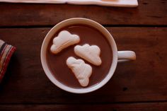 a cup of hot chocolate with marshmallows in the shape of hearts on top