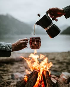 two people are toasting coffee over a campfire