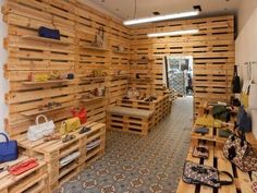 the inside of a store with wooden shelves and handbags on display in front of them