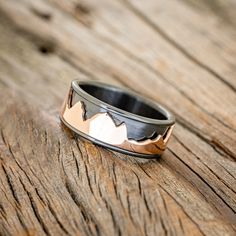 a wedding band with mountains on it sitting on a wooden surface, ready to be used as a ring