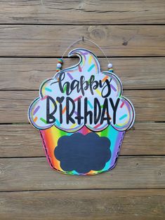 a happy birthday cupcake sign hanging on a wooden wall with the words happy birthday painted on it