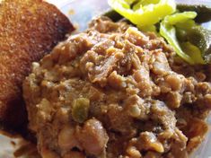 a close up of food on a plate with pickles and bread in the background