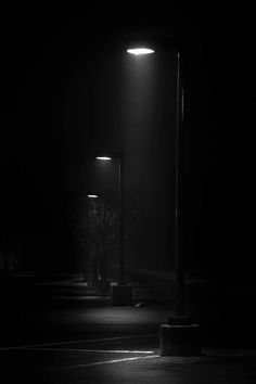 two street lights are lit up in the dark at night, with only one light on