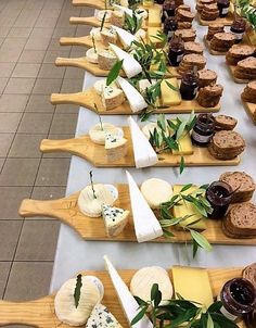 a long table topped with lots of different types of cheeses and crackers on wooden paddles