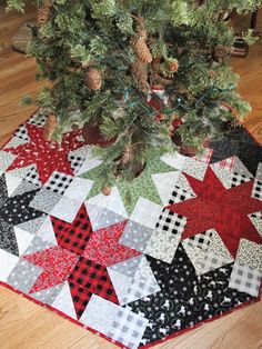 a quilted christmas tree skirt is on the floor next to a small pine tree