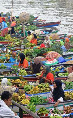 many people in boats filled with fruits and vegetables on the water's edge,