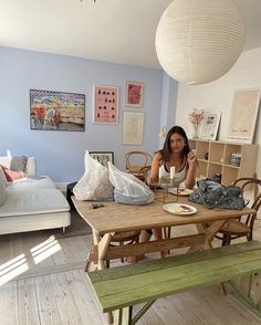 a woman sitting at a wooden table with food on it in front of a bed