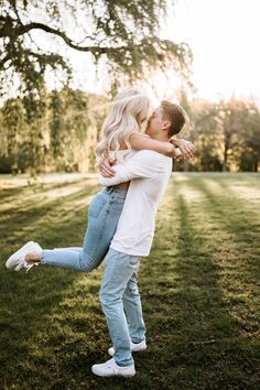 a man and woman hugging each other in the grass