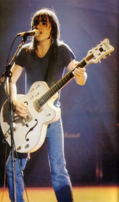 black and white photo of a man playing guitar on stage with microphone in front of him