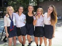 four girls in school uniforms posing for the camera