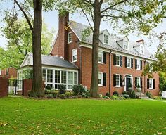 a large red brick house with white trim and windows on the front, surrounded by trees