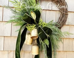 a christmas wreath with bells and greenery hanging on a wooden wall next to a door