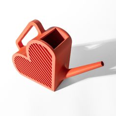 an orange heart shaped container sitting on top of a white table