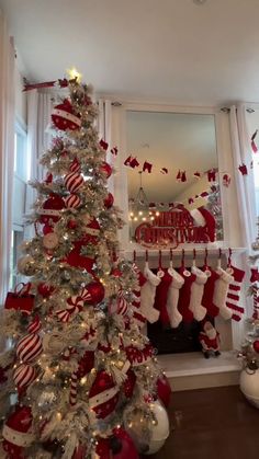 a christmas tree with stockings hanging from it's sides in front of a window