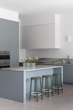 three stools sit at the center of a kitchen island