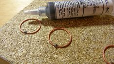 a tube of glue sitting on top of a counter next to two rings and a ring