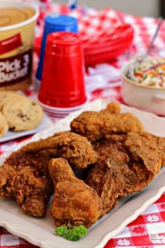 fried chicken is served on a white platter with red and white checkered tablecloth