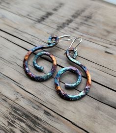 Colorful Copper Spiral Earrings  Each earrings is formed by hand and hammered for texture. The vibrant colors are created using a flame painting technique. Each earring has a unique, one-of-a-kind look. The earrings are sealed to help protect the colors. These colorful earrings swing from sterling silver ear wire and measure approximately 2 inches in total.  Because each earring is handmade, the pair you receive may vary from the ones shown in the photos. The colors may be significantly different- this will also depend on the lighting they are under. The colors are only on one side.  All jewelry come packaged in eco-friendly materials. Spiral Jewelry, Wire Wrapped Jewelry Diy, Mixed Media Jewelry, Spiral Earrings, Colorful Earrings, Wrapped Jewelry, Jewelry Diy