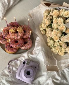 two donuts and flowers on a table with a camera next to one that has candles in it