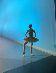 a young ballerina standing in front of a blue wall