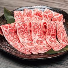 slices of raw meat sitting on top of a black plate