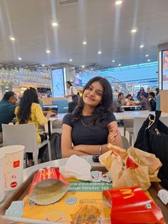 a woman sitting at a table with some food in front of her and smiling for the camera