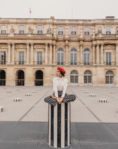 a woman wearing a red hat sitting on top of a black and white pole