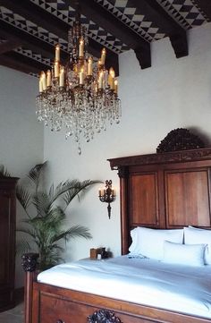 a bedroom with a large bed and chandelier hanging from the ceiling