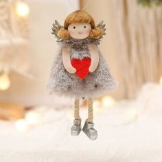 a doll hanging from a string with a heart in it's hands on a bed