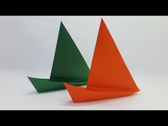 two orange and green paper boats sitting side by side