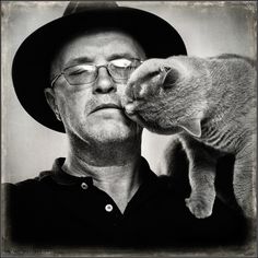 a man in a hat and glasses holding a cat