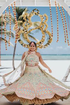 a woman in a dress standing under an arch on the beach